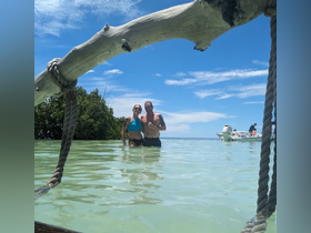 A couple enjoys a sunny day in shallow, clear waters, capturing a memorable moment with a boat in the background — perfect for beach adventures and romantic getaways.