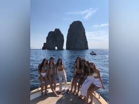 A group of friends enjoys a sunny day on a boat near iconic rock formations, perfect for memorable beach outings and celebrations.