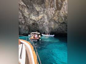 A group of guests explores a stunning cave by boat, surrounded by crystal-clear turquoise waters — a perfect adventure for nature lovers.