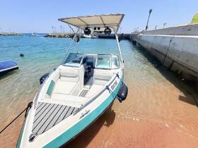 A sleek speedboat docked on a sandy shore, showcasing its stylish design and inviting waters, perfect for a day of adventure on the sea.