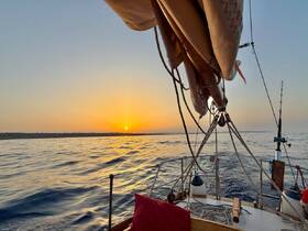 A serene sunset view from the deck of a sailboat, showcasing the tranquil waters and the beauty of the evening sky — perfect for romantic cruises or peaceful sailing adventures.