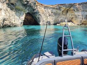 A stunning view of a boat approaching a picturesque cave along a rocky coastline, showcasing the vibrant turquoise waters — perfect for exploring hidden gems on a boating adventure.