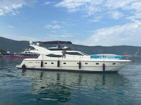 A yacht glides through calm waters with a person enjoying the view on deck, showcasing the perfect setting for a day on the water.