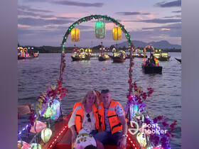 A couple enjoys a scenic evening boat ride adorned with colorful lanterns, surrounded by other illuminated boats on the water — a magical experience perfect for romantic outings.