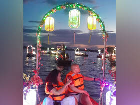 A couple enjoys a scenic evening boat ride adorned with colorful lanterns, creating a magical atmosphere perfect for celebrations.