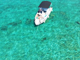 Aerial view of a boat anchored in crystal-clear turquoise waters, perfect for a relaxing day on the water.