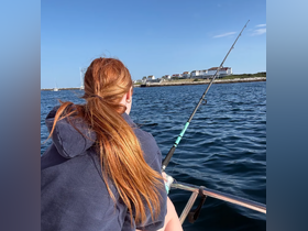 A young girl enjoys a fishing trip on a boat, casting her line into the sparkling water — a perfect day for fishing and creating memories on the water.