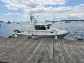 A fishing boat is docked at the pier, showcasing its sleek design against a backdrop of a serene harbor filled with other vessels.