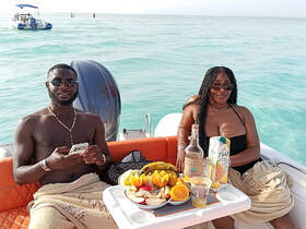 A couple enjoys a relaxing day on the water with cocktails and fresh fruit, capturing the essence of a perfect boat getaway.