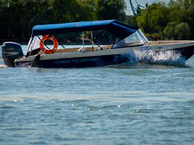 A Corsar 730 Bowrider glides through the water, showcasing its sleek design and vibrant colors, perfect for a day of fun on the water.