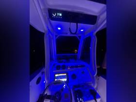 A nighttime view of the helm inside a boat, featuring illuminated controls and a modern console, perfect for navigating the waters after dark.