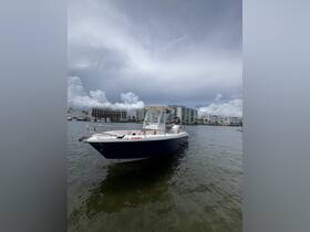 A sleek speedboat docked in calm waters, showcasing its stylish design against a backdrop of cloudy skies and waterfront buildings.