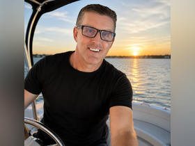 A man takes a selfie while enjoying a sunset on the water, capturing the essence of a perfect boating experience.