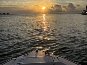 A serene sunset view from the bow of a boat, reflecting golden hues on the water's surface — perfect for tranquil evening cruises.