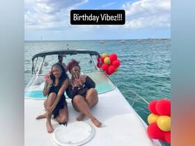 Two friends celebrate a birthday on the deck of a boat, enjoying the vibrant atmosphere with festive decorations and the beautiful ocean backdrop.