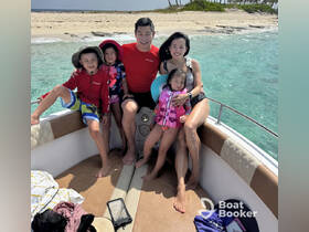 A joyful family enjoys a sunny day on a boat, surrounded by clear waters and a sandy beach — perfect for creating unforgettable summer memories.
