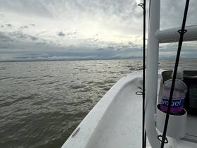 A serene view of a fishing boat's hull against a cloudy ocean backdrop, perfect for fishing enthusiasts seeking adventure on the water.