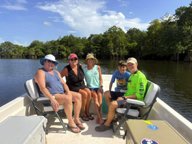 A cheerful group of friends and family enjoy a sunny day on the water, creating lasting memories aboard their boat on a serene lake.