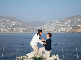 A romantic proposal unfolds on the deck of a yacht, capturing a special moment against a stunning coastal backdrop — perfect for unforgettable celebrations.
