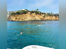 Two snorkelers enjoy the clear waters near a stunning coastal cliff, showcasing the perfect setting for aquatic adventures.
