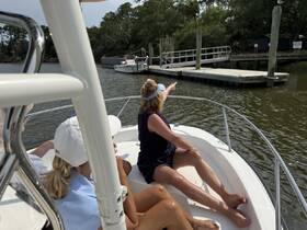 A group of friends enjoys a scenic boat ride, with one person pointing out a nearby dock along the waterway — perfect for exploring local attractions.