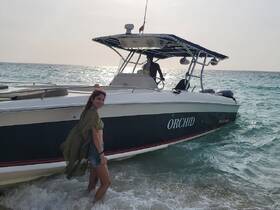 A woman enjoys a sunny day at the beach next to the 'Orchid' boat, capturing a moment of fun and relaxation in the water.