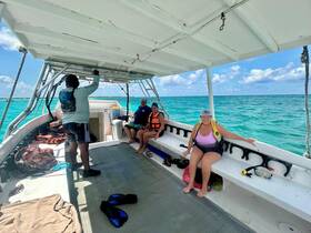 A group of guests relaxes inside a boat, preparing for snorkeling adventures in vibrant turquoise waters. The interior setup showcases seating and snorkeling gear, ideal for a fun day on the water.