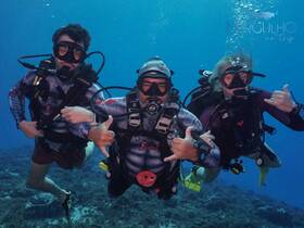A group of divers poses underwater, showcasing the thrill of scuba diving — an unforgettable adventure in the ocean's depths.
