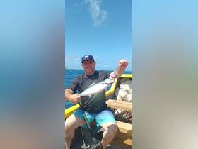 A proud angler displays his catch while fishing on a boat in the open ocean, showcasing the thrill of a successful day on the water.