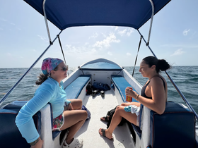 Two friends relax on a boat, enjoying the ocean view and each other's company — a perfect moment for a day out on the water.