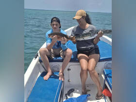 A mother and her son proudly display their fishing catch while enjoying a day on the water — a perfect family bonding experience in the ocean.