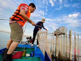 Two individuals actively engaged in fishing from a boat, showcasing a hands-on experience on the water. This scene captures the essence of aquatic adventures and local fishing practices.