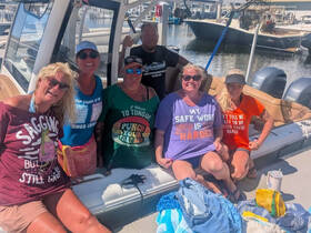 A lively group of friends enjoys a fun day on the boat, showcasing their playful shirts and camaraderie — perfect for a memorable boating experience.