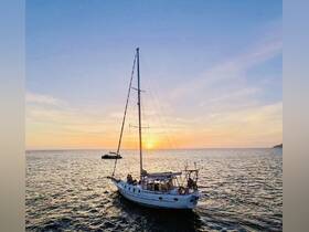 A beautiful sunset view featuring a sailing yacht on the ocean, with guests enjoying the serene atmosphere — perfect for romantic getaways or sunset cruises.