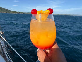 A vibrant cocktail is held against a stunning ocean backdrop, perfect for enjoying refreshing drinks while sailing or relaxing on the water.