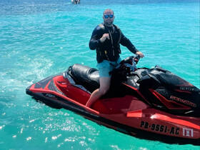 A man enjoys an exhilarating ride on a jet ski in crystal-clear waters, showcasing the thrill of water sports and adventure on the ocean.