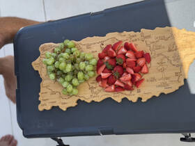 A beautifully arranged platter of fresh grapes and strawberries on a wooden board, perfect for enjoying snacks while on a boat trip.