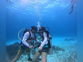 A couple shares a romantic moment underwater while scuba diving, surrounded by the vibrant marine life — an unforgettable experience in the ocean.