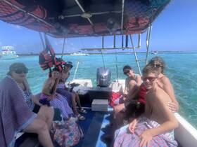 A cheerful group of family members enjoys a day on the water, capturing the essence of fun and relaxation aboard their boat in a beautiful turquoise setting.