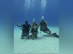 A group of divers poses underwater, showcasing the excitement of scuba diving in crystal-clear waters — an unforgettable adventure for ocean enthusiasts.