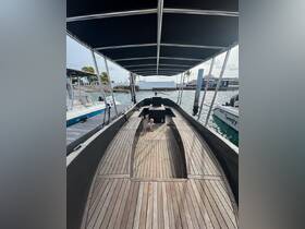 A cozy interior view of a boat featuring a child sitting on the wooden deck, showcasing the spacious seating area perfect for family outings.