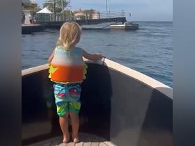 A child in a colorful life jacket enjoys the view from the bow of a boat, capturing the essence of family adventures on the water.