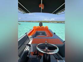 Interior view of a sleek boat featuring vibrant orange seating and a modern helm, perfect for comfortable cruising on clear turquoise waters.