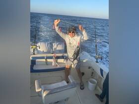 A joyful angler celebrates a successful fishing trip, proudly displaying his catch aboard a boat — a perfect moment for fishing enthusiasts.