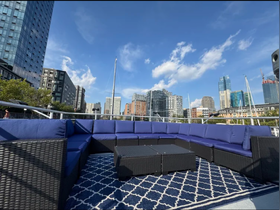 A stylish lounge area on a boat featuring comfortable seating and a scenic view of the city skyline — perfect for relaxing while enjoying the water.