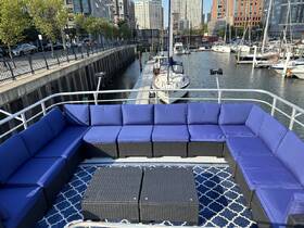 A cozy lounge area on a boat featuring plush blue seating and a stylish table, perfect for relaxing while enjoying views of the marina.