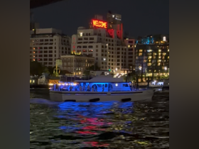 A lively boat illuminated at night, cruising through the city waters, creating a vibrant atmosphere perfect for celebrations and nightlife experiences.