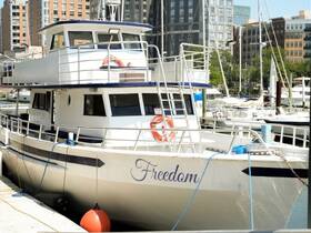 A clear view of the 'Freedom' boat docked at the marina, showcasing its structure against a backdrop of urban buildings.