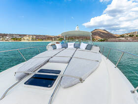 A stunning view of the deck of a yacht, featuring spacious lounging areas and a backdrop of serene waters and hills, perfect for relaxing on the open sea.