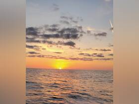 A stunning sunset over the ocean, capturing the vibrant colors reflecting on the water — perfect for serene evening boat rides.